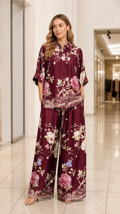 Model wearing burgundy floral print satin two-piece shirt and pants set