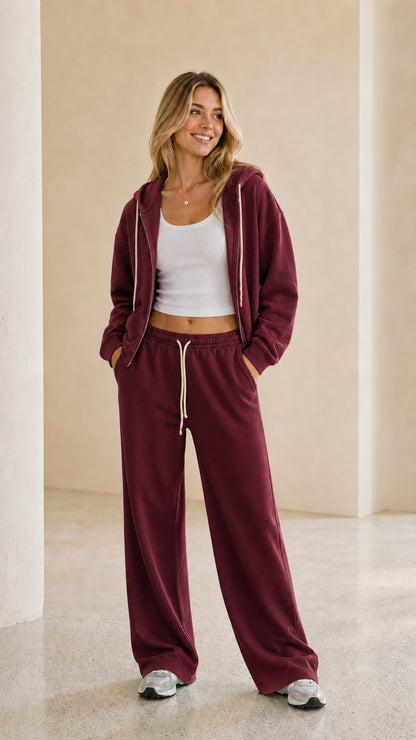 Model wearing burgundy zip-up hoodie and wide leg pants tracksuit