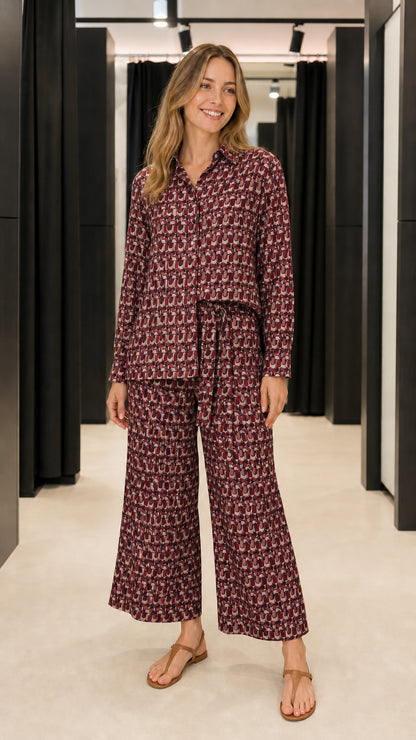 Woman wearing burgundy geometric print matching shirt and trousers set