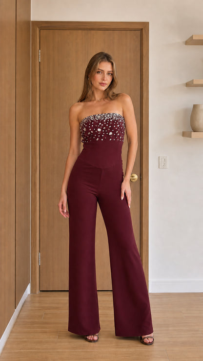 Model wearing burgundy crystal embellished strapless jumpsuit