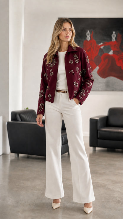 Woman wearing Burgundy embellished floral zip-up jacket with white trousers
