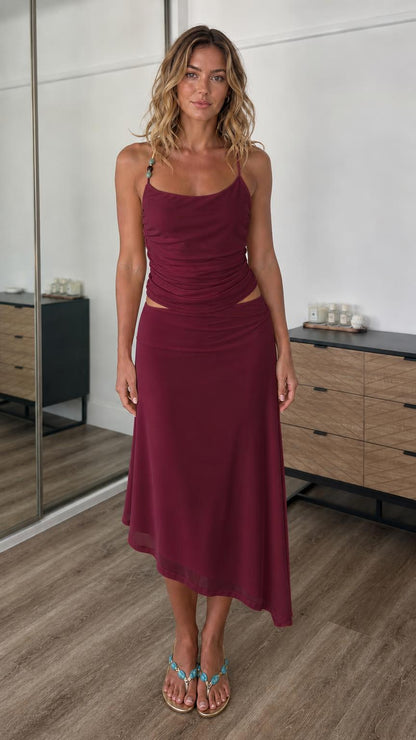 Front view of model wearing burgundy two-piece cami top and midi skirt set