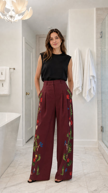 Front view of model wearing burgundy floral embroidered wide-leg trousers