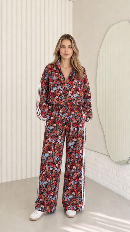 Woman wearing burgundy floral print zip-up tracksuit two-piece set