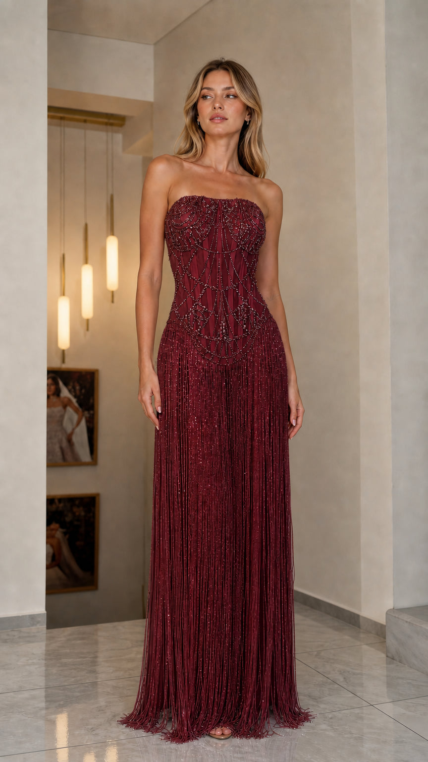 Front view of model in burgundy red strapless beaded fringe gown