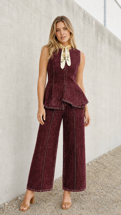 Front view of model wearing burgundy denim peplum top and wide-leg pants set