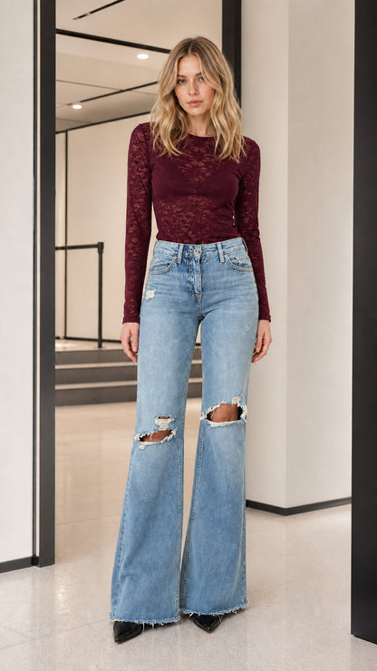 Model wearing burgundy long-sleeve sheer lace top with flare jeans