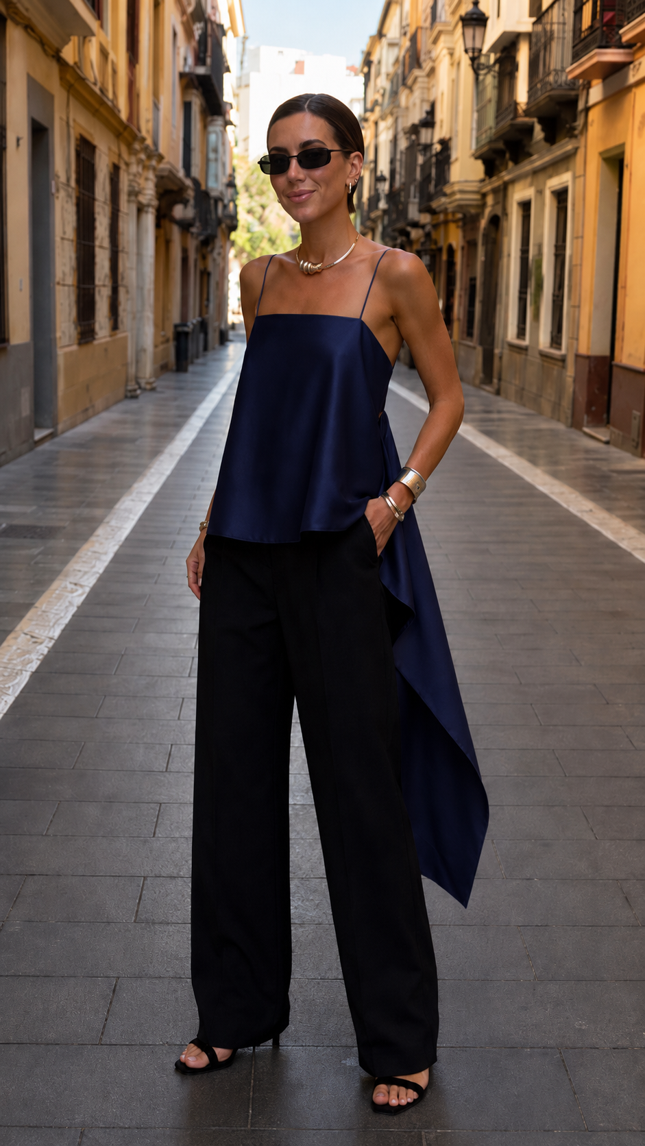 Front view of navy asymmetric draped cami top with black trousers