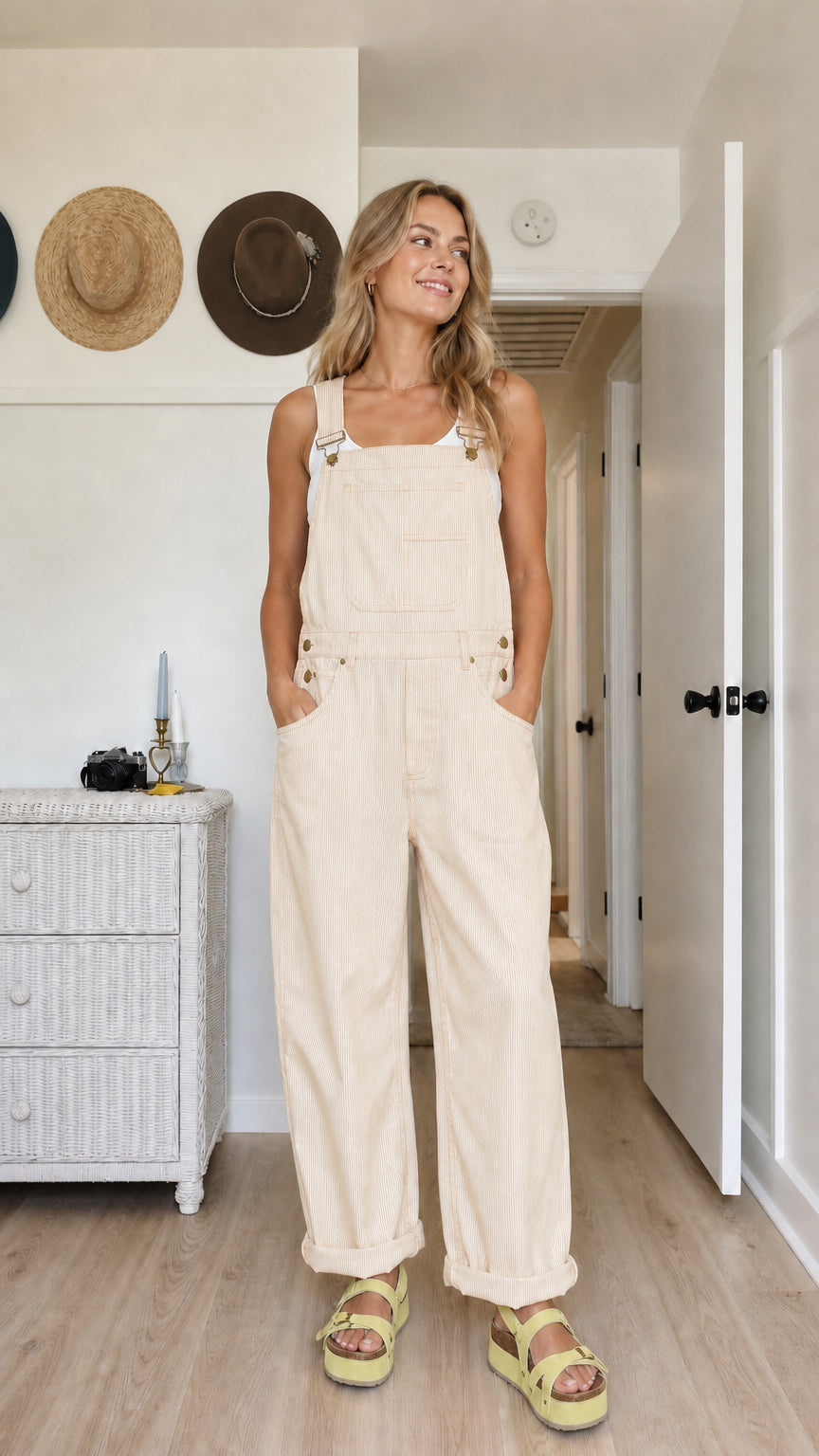 Model wearing cream wide-leg bib overalls with rolled hems and utility pockets