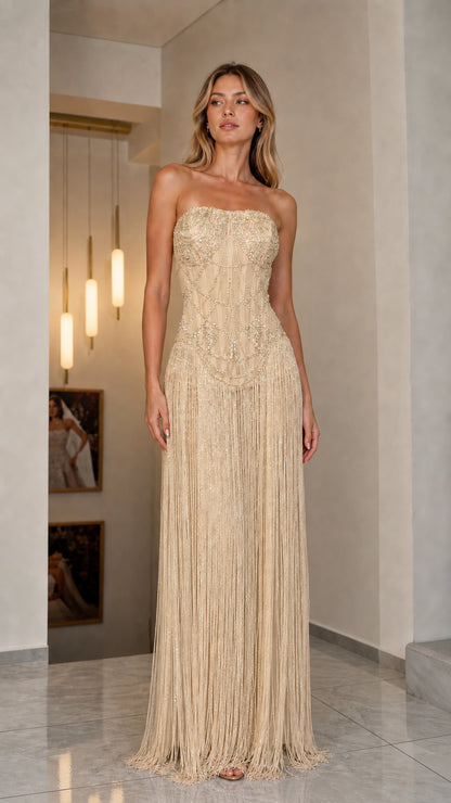 Front view of model in champagne gold strapless beaded fringe gown