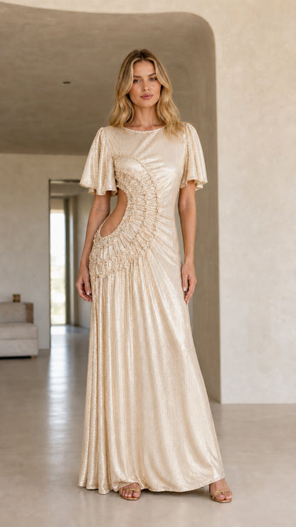Front view of woman wearing the champagne color variant of the metallic cutout maxi dress