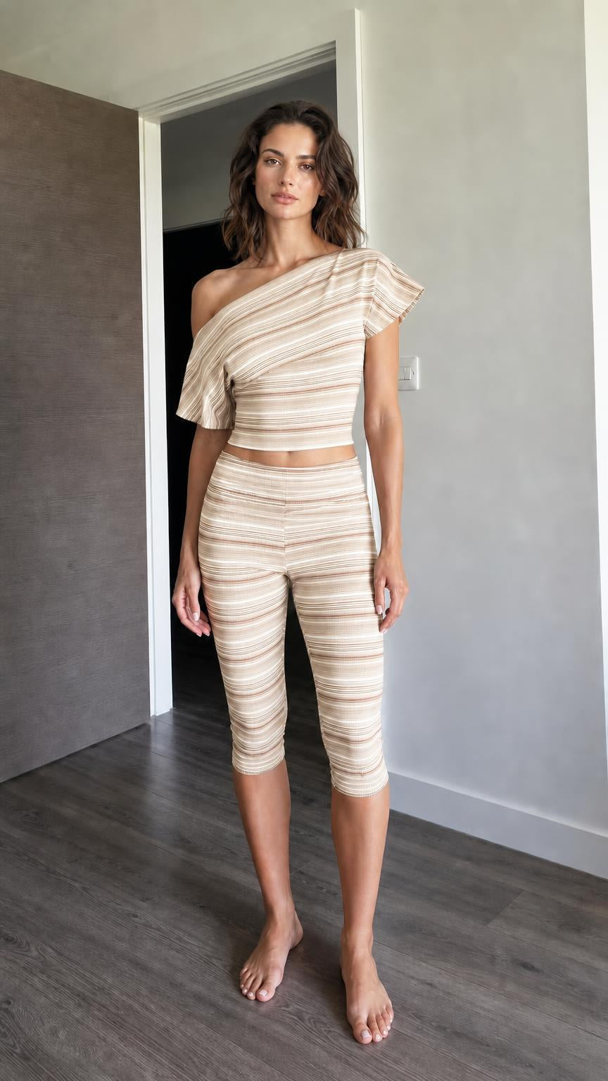 Woman wearing beige striped one-shoulder crop top and capri leggings set