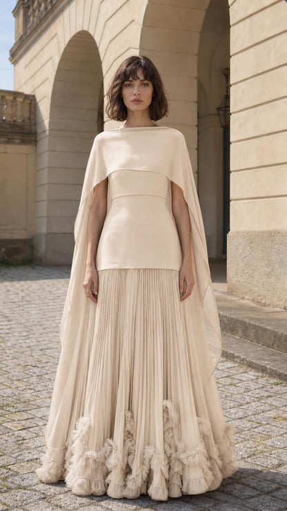 Front view of woman wearing champagne cape overlay pleated maxi dress