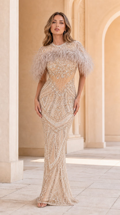 Model wearing Champagne gold beaded evening gown with feather trim