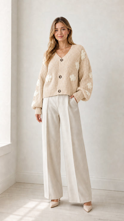 Model wearing beige cream chunky knit V-neck cardigan with white floral appliqués