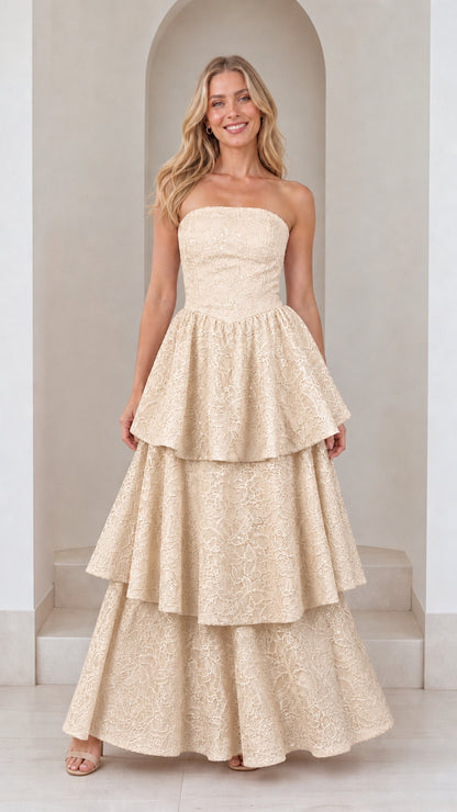 Front view of model in champagne strapless tiered maxi dress