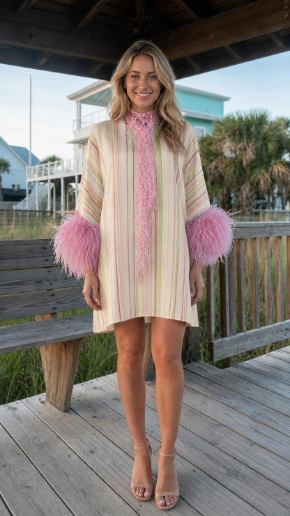 Front view of model wearing cream stripe dress with pink feather cuffs